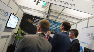 A group of delegates huddle round the Assure360 stand at Expo