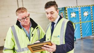 Workers review an electronic plan of work before beginning asbestos removal